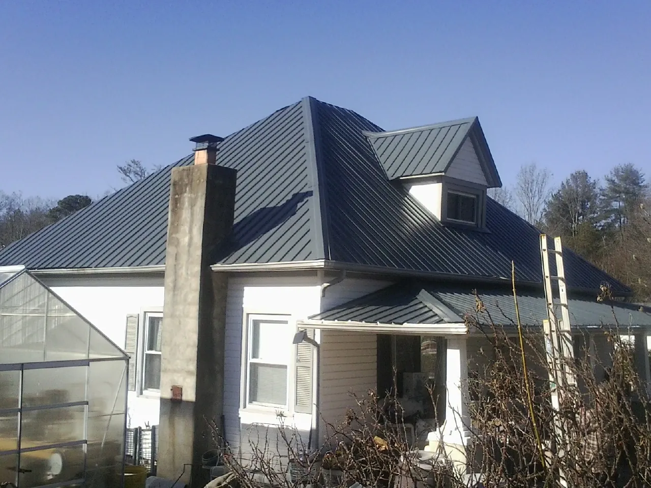 Dark blue standing seam metal roof on a white farmhouse with dormer — Slate & Tile Roof Repair by Roofing Brothers in Havertown
