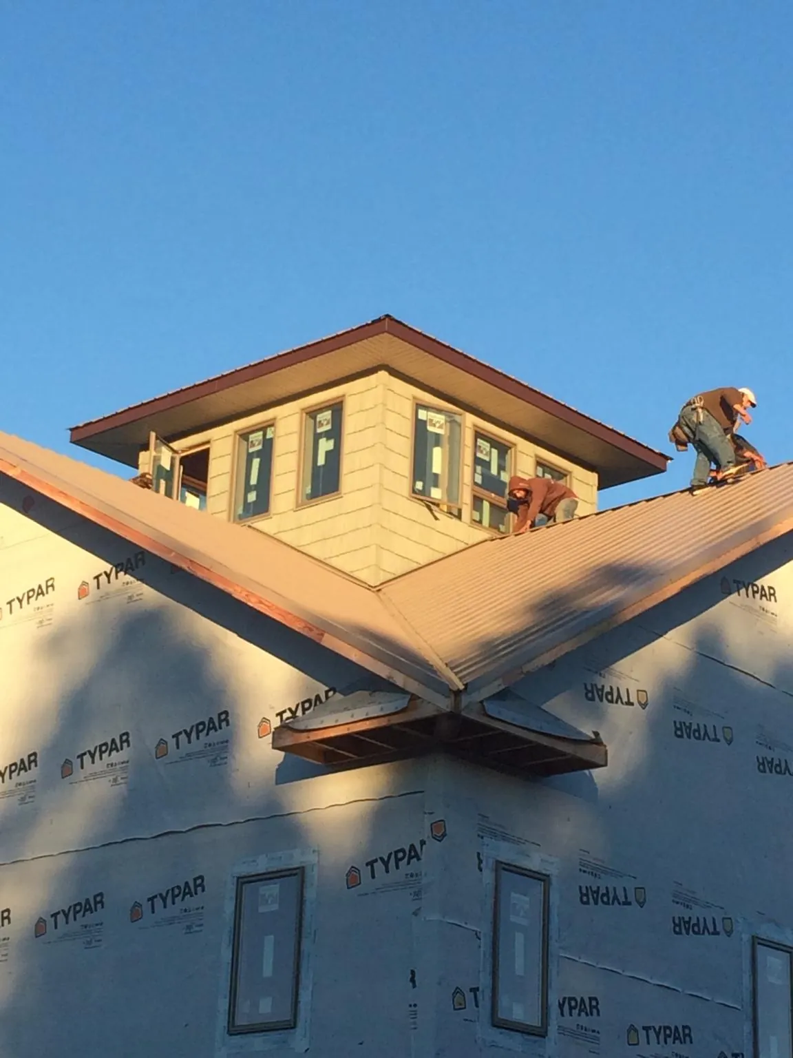 Roofers working around a rooftop cupola on a new metal roof at sunset — Roof Waterproofing in Havertown by Roofing Brothers
